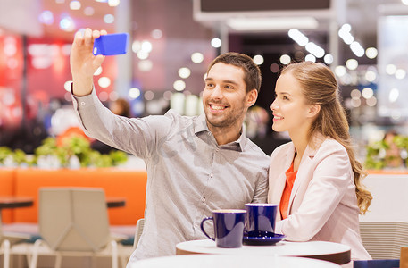 手机购物商城摄影照片_幸福的夫妻在商场里用智能手机自拍