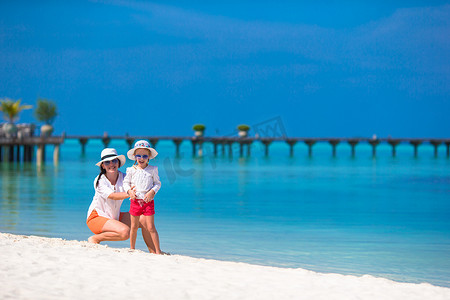海滩度假期间快乐的小女孩和年轻母亲