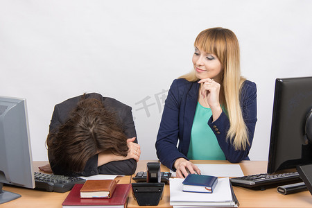 办公室里的情况——沮丧的女人躺在桌子上，她的同事傲慢地看着她