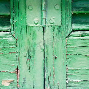 在旧墙上有一扇铰链窗，绿色的木头和生锈的金属