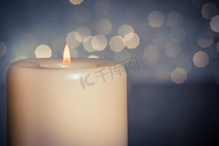 火焰蓝摄影照片_蓝色散景背景中木桌上火焰蜡烛的特写
