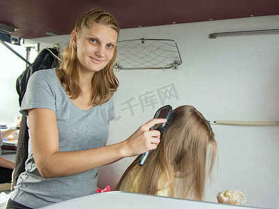 母亲在火车的小床上梳理女儿的长发