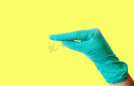 一只戴着蓝色乳胶手套的女性手在浅黄色背景上做出类似于鸭嘴孤立的手势。