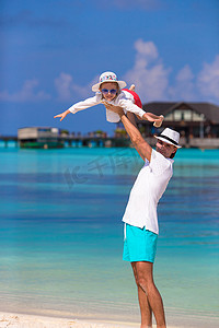 热带海滩度假期间可爱的小女孩和快乐的父亲