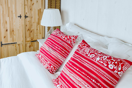 在卧室的红色枕头有白色床单和灯的