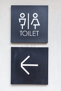 箭头标志摄影照片_混凝土墙式精品店上的男女通用厕所或厕所和箭头标志