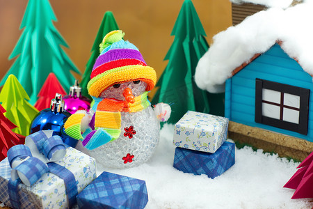 装饰小星星摄影照片_雪人和礼品盒与小星星纸在雪地上。