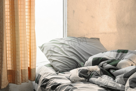 床和被子摄影照片_橙色的格子呢枕头和床上皱纹凌乱的毯子