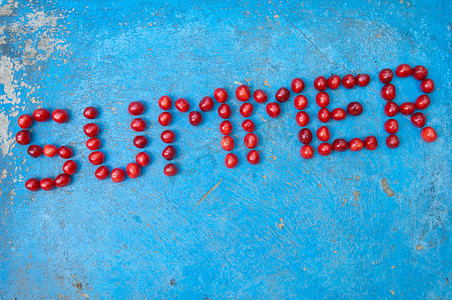 word纹理摄影照片_Word Summer 由带纹理的蓝色背景上的樱桃制成