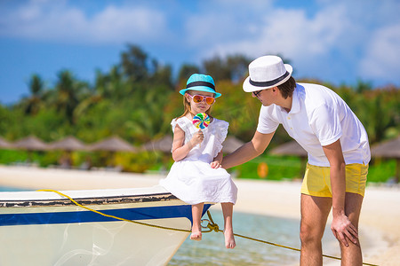 家庭度假摄影照片_热带海滩度假期间的小女孩和爸爸