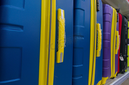黄金卖场摄影照片_货架上成排的蓝色和黄色手提箱或旅行袋