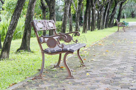 有图案的椅子摄影照片_公园里的钢制长椅，上面有草和砖块。