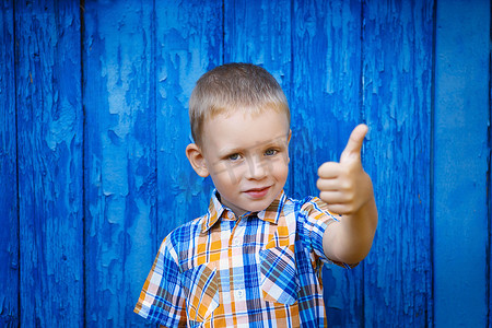 快乐快乐的漂亮小男孩用拇指 ag 打手势的画像
