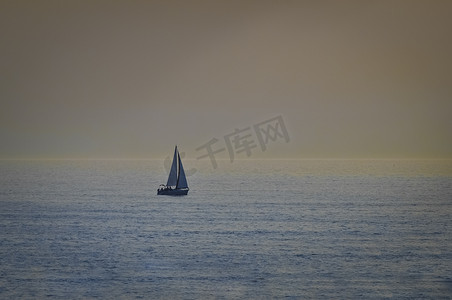 大海航行的船摄影照片_日落时分在大海中航行的小船