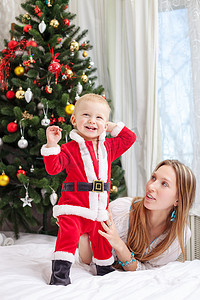 母亲和穿着圣诞老人服装的婴儿玩耍