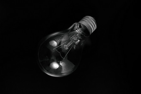 白炽灯充电摄影照片_在黑色背景上的白炽灯泡。