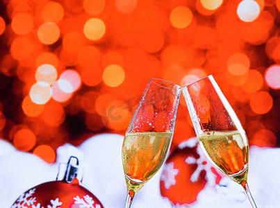 大气圣诞红色摄影照片_红色圣诞灯散景和球装饰背景上带有金色气泡的香槟长笛