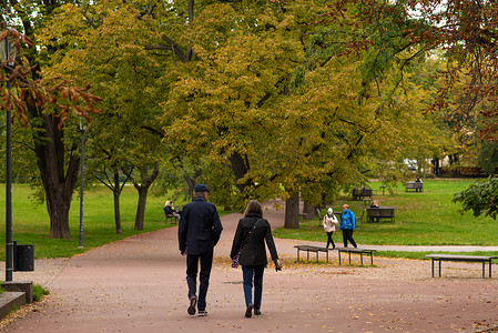秋季保健摄影照片_2020 年秋季，捷克共和国冬季开始时，由于 COVID-19 的爆发，在隔离期间，男人和女人正在布拉格 6 号的莱特纳公园散步和交谈