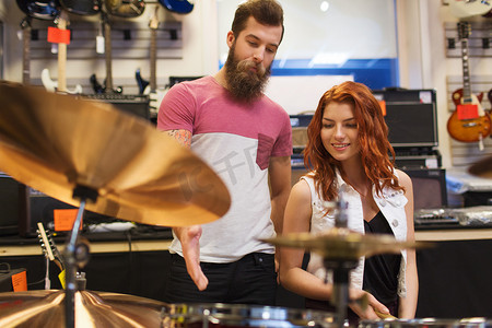 架子鼓摄影照片_音乐商店里带架子鼓的男人和女人