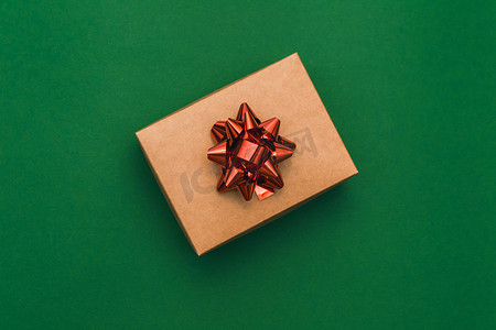 圣诞蝴蝶结边框摄影照片_圣诞边框与工艺礼品盒和绿色背景上的红色蝴蝶结。