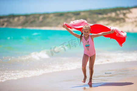 蓝色可爱风摄影照片_小女孩在热带假期玩沙滩巾
