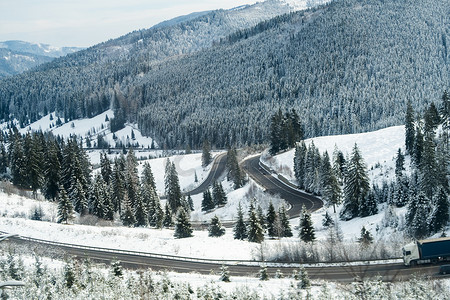 罗马尼亚摄影照片_山区道路弯曲，卡车在路上 — 罗马尼亚冬季大雪后的山景