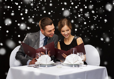圣诞节菜单摄影照片_面带微笑的情侣在餐厅拿着菜单