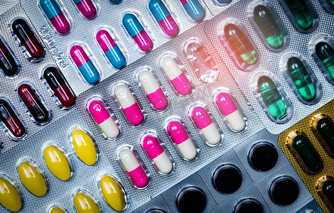 药片图案摄影照片_泡罩包装中五颜六色的药片和胶囊药丸的顶部视图排列着美丽的图案。