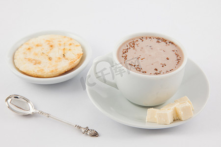 热巧克力摄影照片_一杯热巧克力配奶酪和 arepa 放在白色盘子里