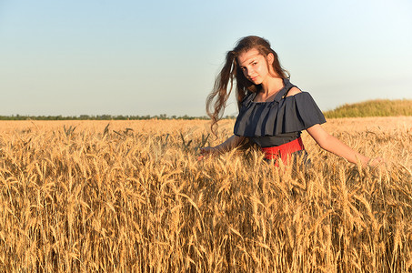 黄金麦摄影照片_一位穿着长发的妇女站在田间的麦群中