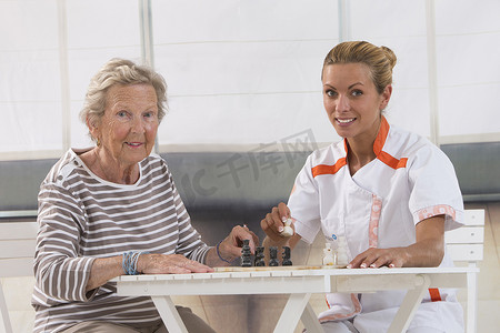 草坪和人摄影照片_在养老院和护士玩耍的老年妇女
