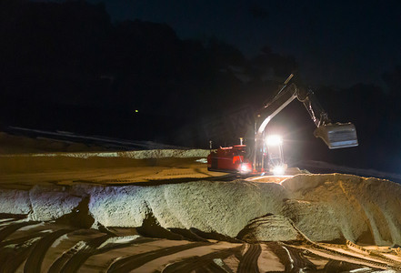 夜间工作的挖掘机挖掘机在海滩上移动地面进行维护