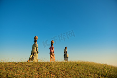 步行回家摄影照片_亚裔缅甸传统农民步行回家