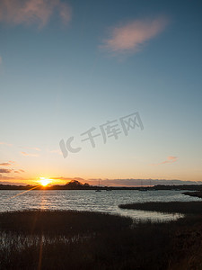 太阳表面摄影照片_太阳落山地平线蓝色水天空表面侧影海岸海洋