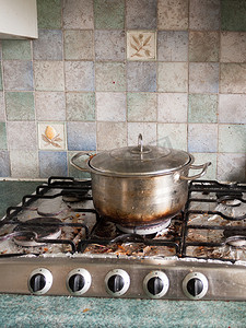 一个带盖子的大银色金属锅，上面有烧焦的黑色和 Br