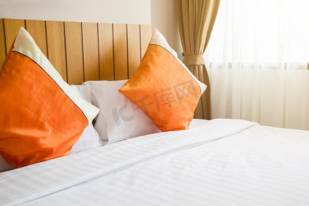 带照明的卧室床上的橙色枕头和白色毯子