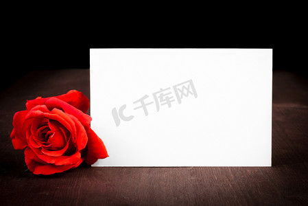 红玫瑰和空白礼品卡，用于旧木背景上的文字
