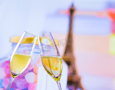 埃菲尔铁塔装饰摄影照片_模糊的埃菲尔铁塔背景上一对带有金色气泡的香槟长笛