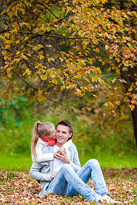 温暖的日子里，和爸爸在秋天公园里的可爱小女孩