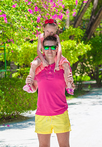 家庭度假摄影照片_热带海滩度假期间的小女孩和年轻父亲