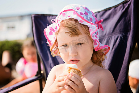 吃冰淇淋摄影照片_海滩度假吃冰淇淋的小女孩
