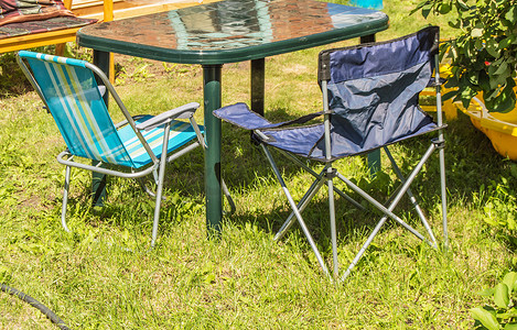 阳光明媚的夏日在草地上露营的塑料折叠桌和折叠椅
