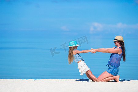 家庭度假摄影照片_海滩度假期间的小女孩和年轻母亲