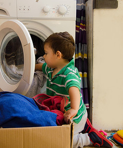 洗衣服男孩摄影照片_一岁半男婴把衣服放进洗衣机