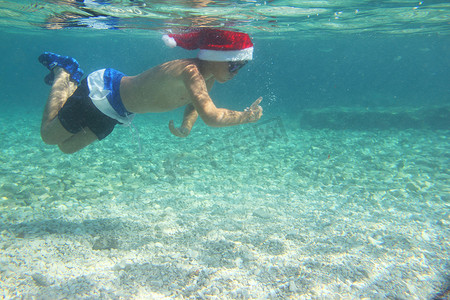 戴着圣诞帽的男孩在海中游泳