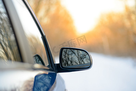 夕阳下冬季风景中汽车侧后视镜的特写图像
