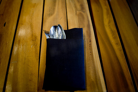 木桌背景中深蓝色布料的叉子和勺子