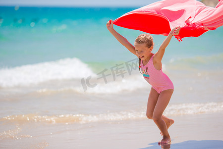 蓝色可爱风摄影照片_小女孩在热带假期玩沙滩巾