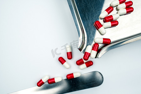 不锈钢药物托盘上红色、白色抗生素胶囊药丸的俯视图。