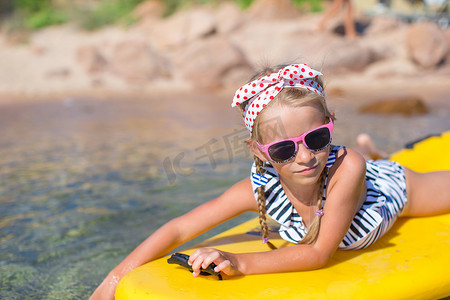 蓝色大海摄影照片_暑假期间在蓝色大海中划皮划艇的可爱小女孩
